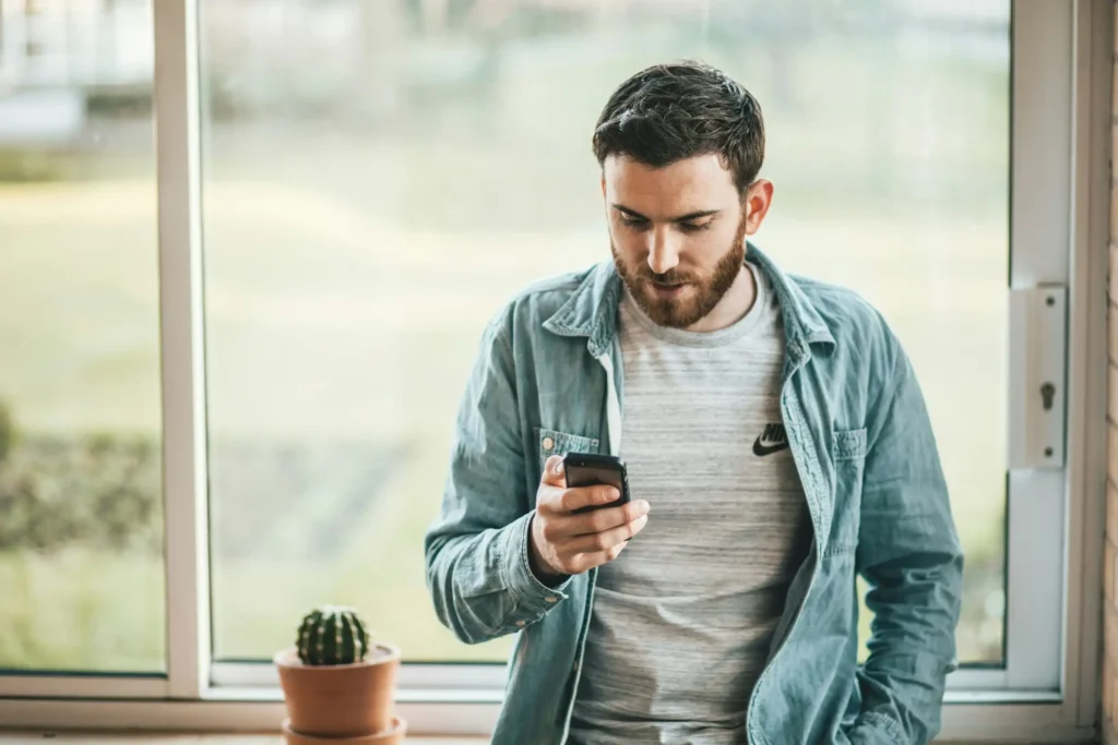 man-holding-a-smartphone-near-the-window